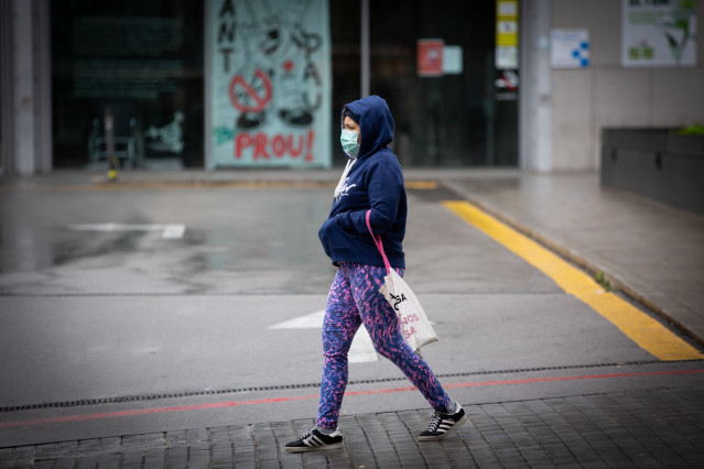 Una mujer pasa por las inmediaciones de la Estación de Barcelona Sants durante el día en el que entra en vigor la limitación total de movimientos salvo de los trabajadores de actividades esenciales, medida adoptada ayer por el Gobierno como prevención del