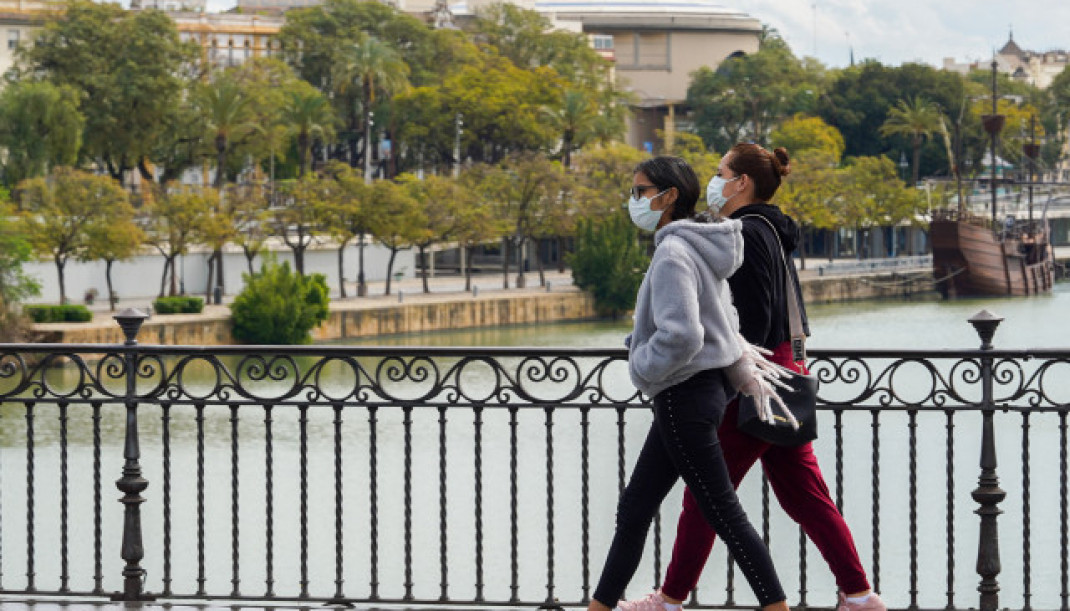 EuropaPress 2721882 dos jovenes mascarillas paseando andando puente triana tercer dia alarma