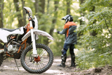 Stylish rider with motorbike parked forrest