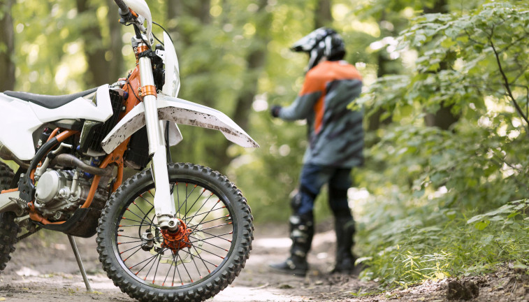 Stylish rider with motorbike parked forrest