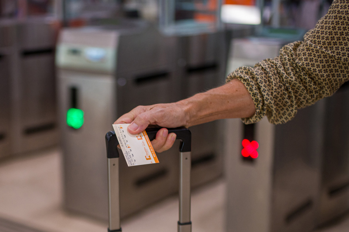 Archivo - Una viajera sostiene un billete de Rodalies.